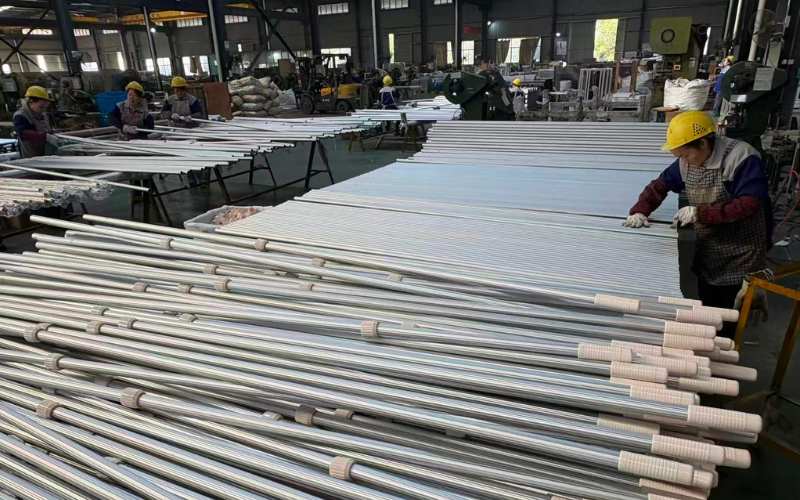 Worker assembling injection-molded plastic locking cam onto anodized aluminum pool telescopic pole at Poolpole assembly line
