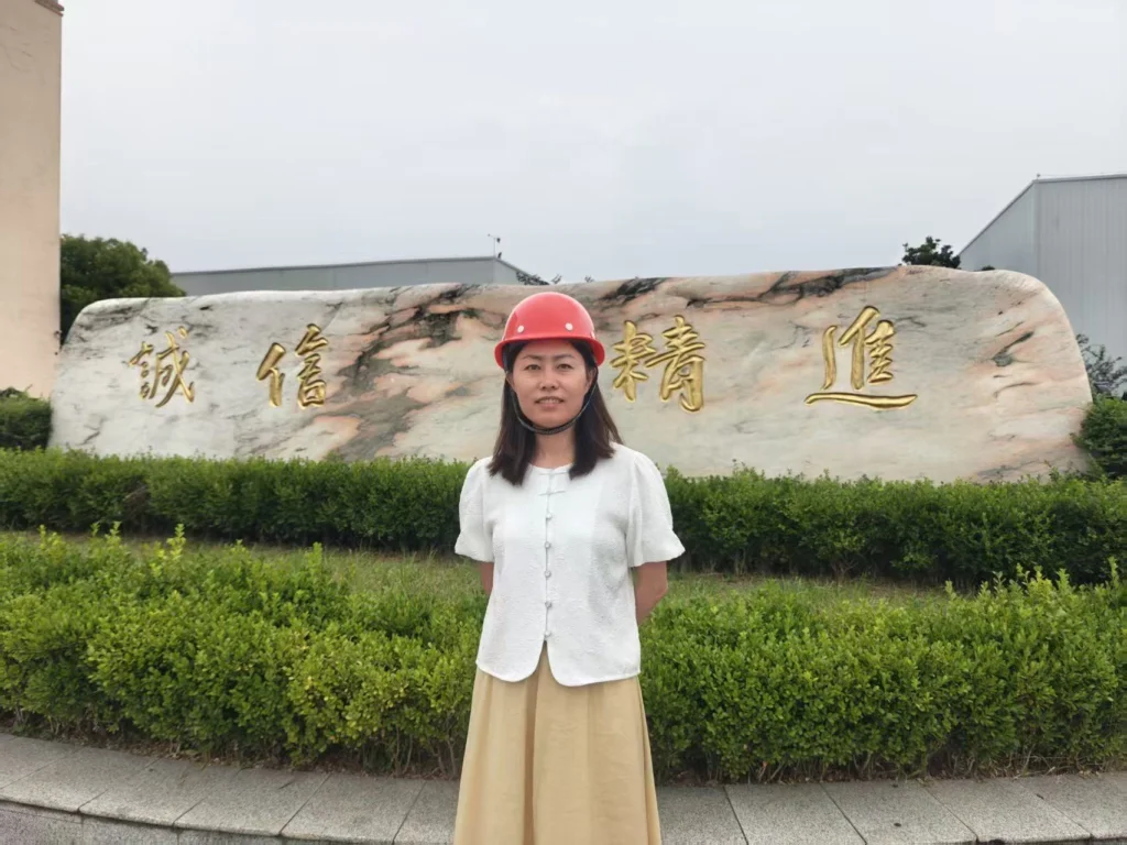 Sophie in a hard hat at the entrance of the Xingyong aluminum plant in Huai'an