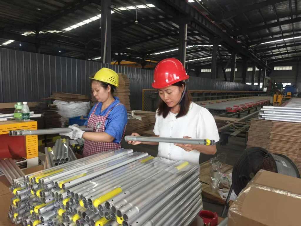 Sophie inspecting an assembled aluminum telescopic pole on the Xingyong packing line