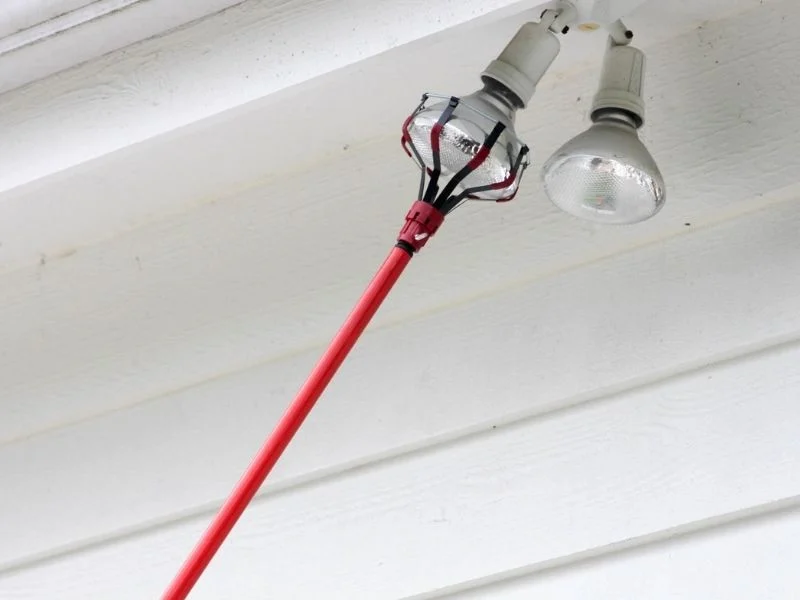 Long‑reach bulb changer pole operated from ground beneath high ceiling, four‑section design.