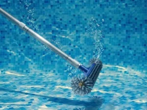 Pool brush head scrubbing a pool wall on an aluminum pole