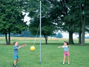 Kids playing tetherball on an aluminum pole in a backyard