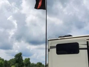Mastro telescópico para bandeira de trailer montado em uma escada de trailer com a bandeira hasteada